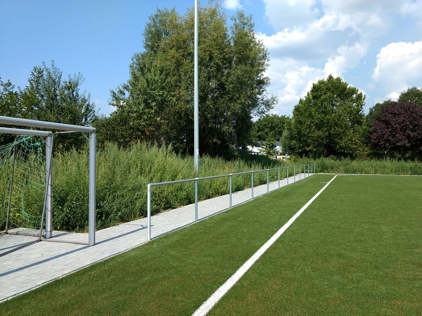 Umlaufenden Pflasterumrandung und Rohrbarrieren am Sportplatz