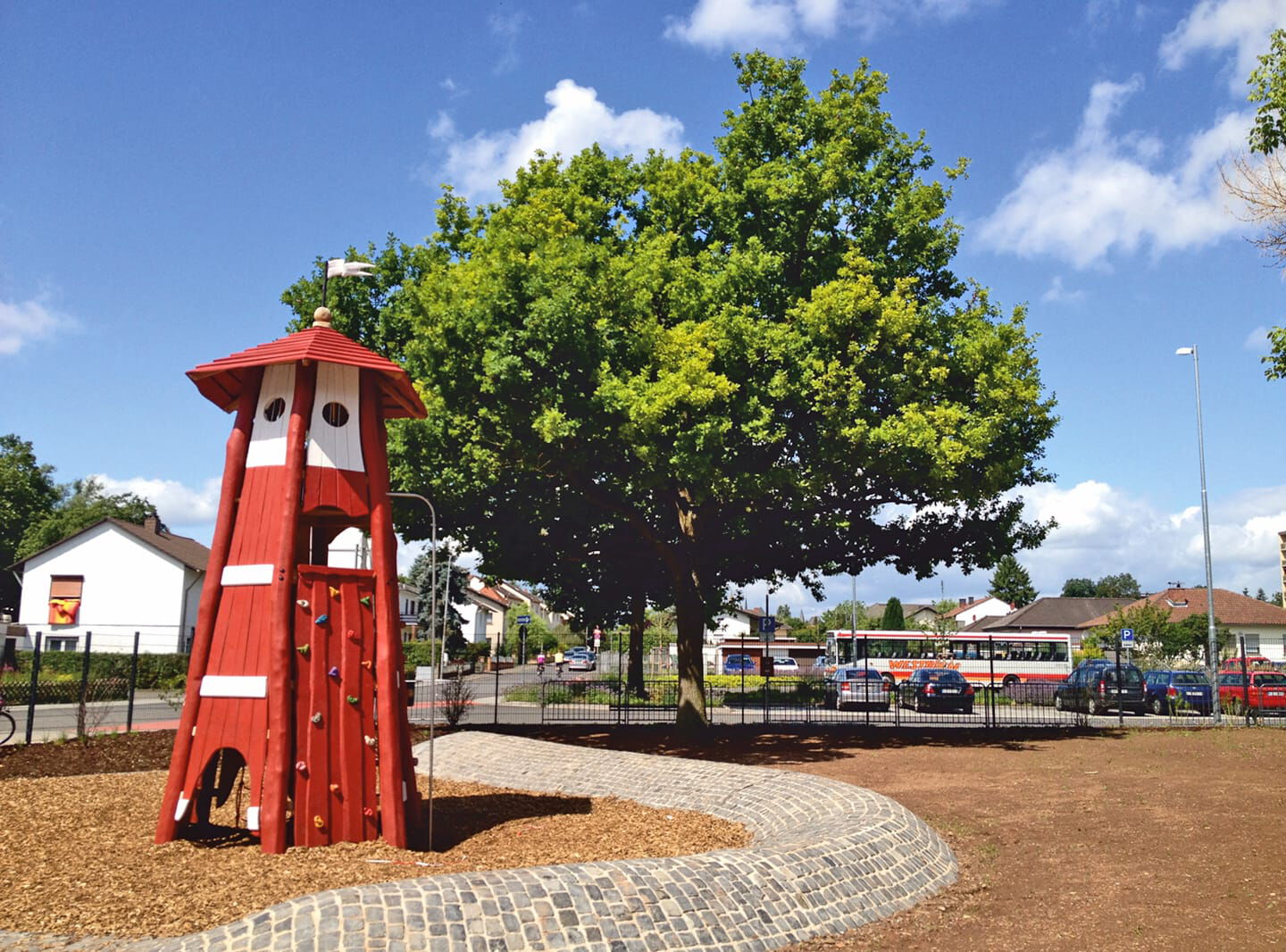 Schulhof mit Bäumen und Kletterturm