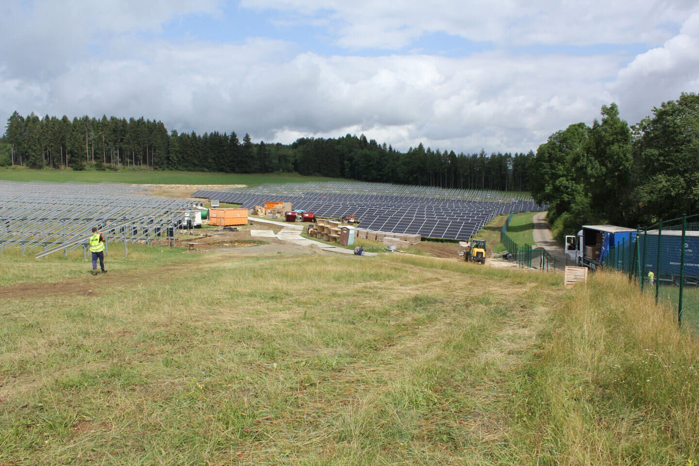 Aufbau einer Solaranlage auf einer Grünen Wiese am Waldrand